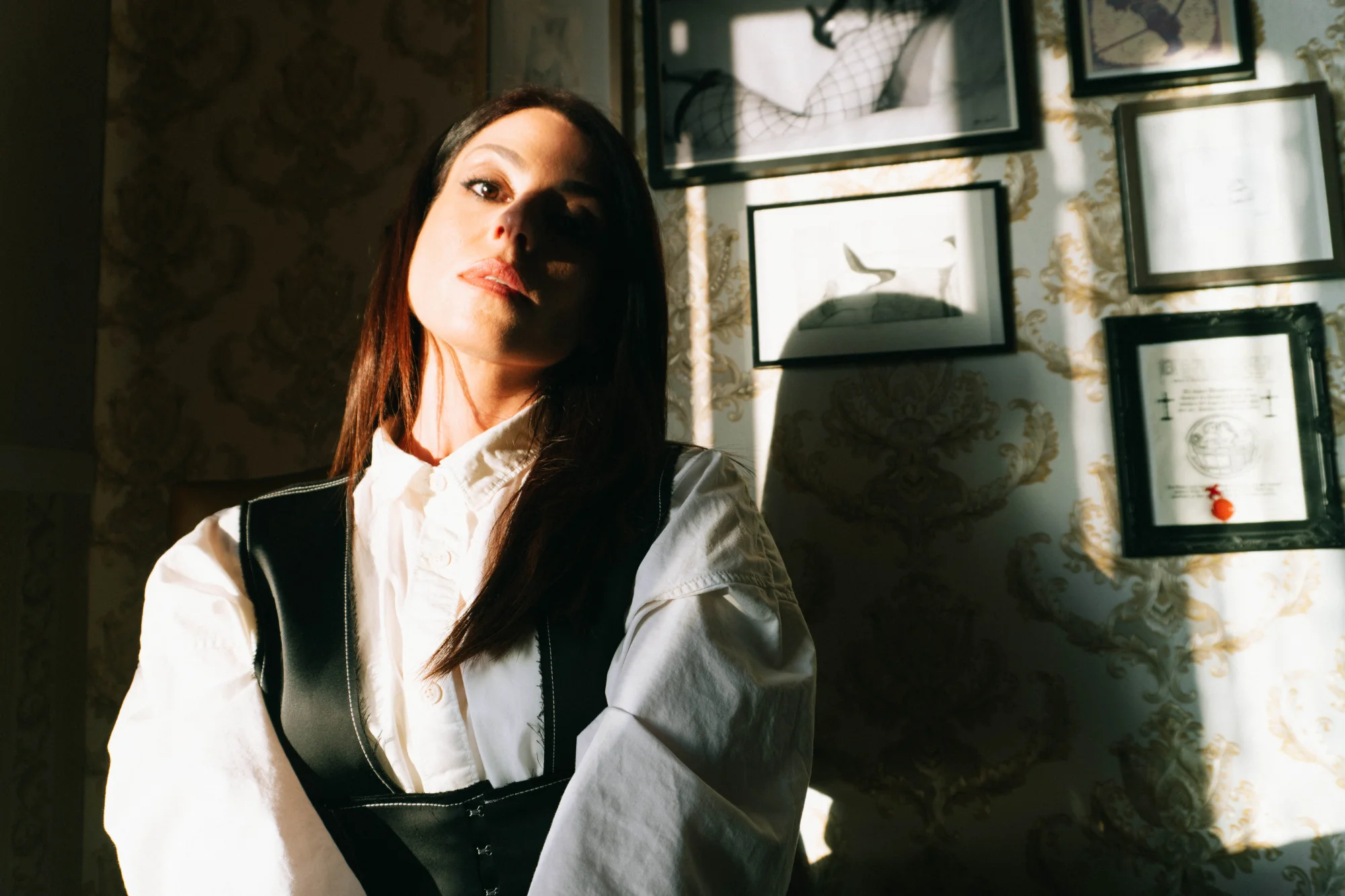 Aido Akida, dominatrix based in Berlin, she is wearing a white shirt and black corset.
