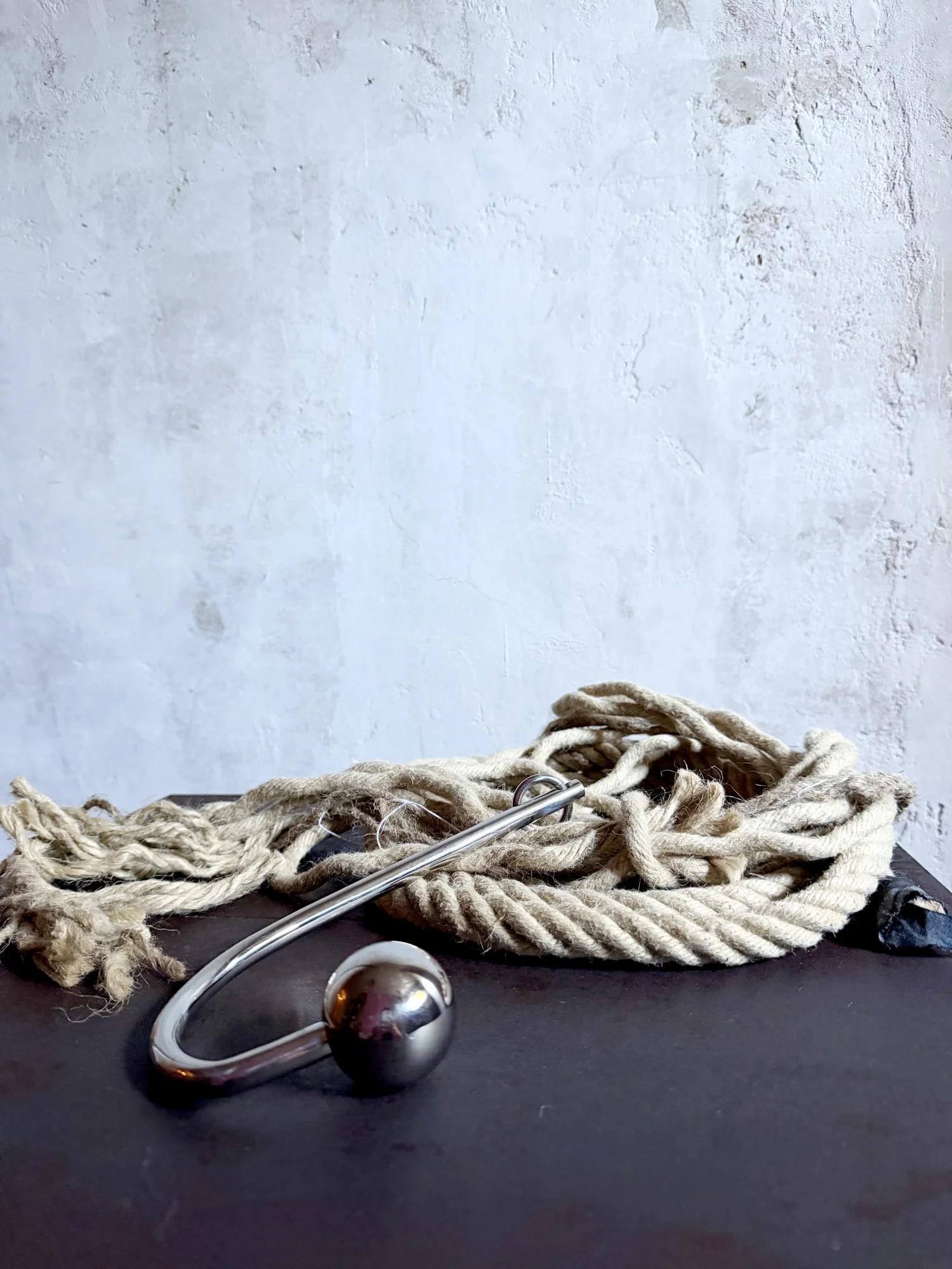 Close up of an anal hook and rope, gray background