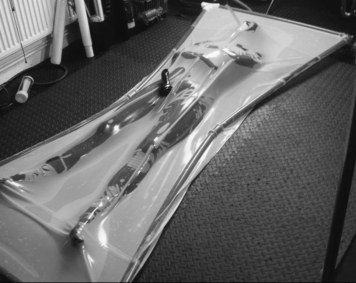 black and white photography of a man inside vacuum bed. Fully sealed with layers of rubber