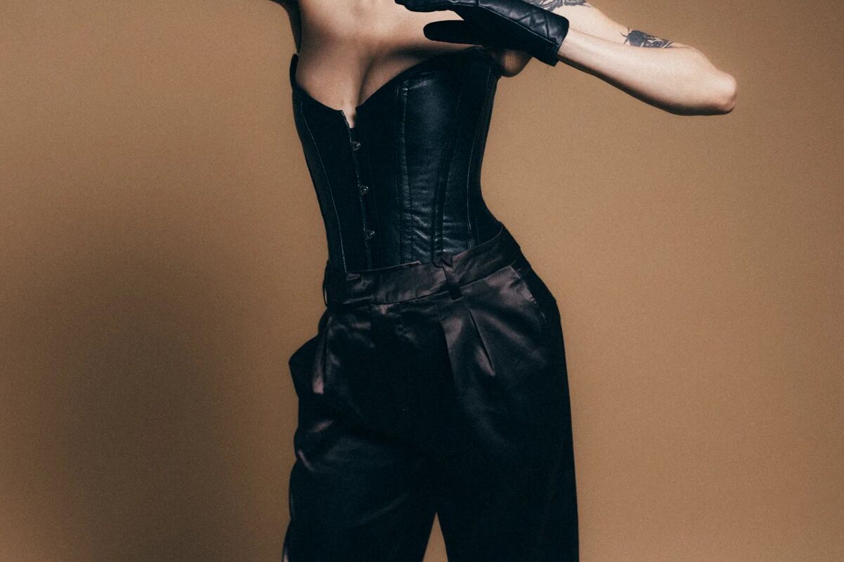 Madame Ava Laffaire, an international dominatrix based in Berlin, is dressed in a leather corset and is taking off her leather glove
