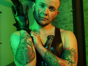 Darius Rex zieht einen Latex-Handschuh im grünen Licht über seine rechte Hand an.
