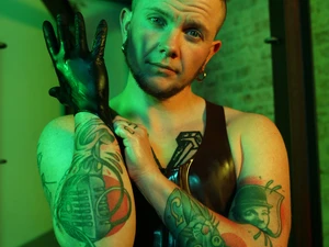 Darius Rex zieht einen Latex-Handschuh im grünen Licht über seine rechte Hand an.