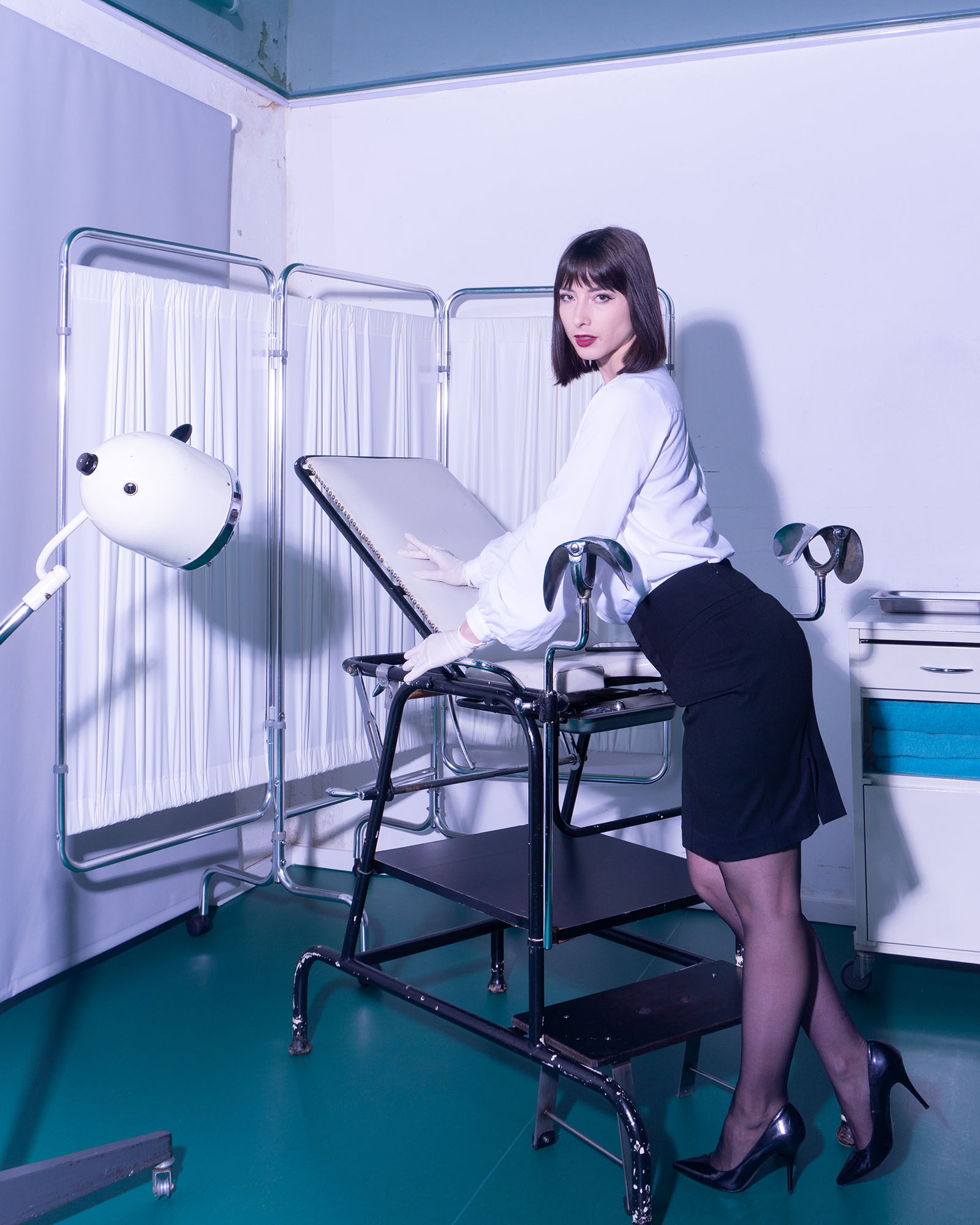 Inara Vesper preparing the gynocological chair for a BDSM session in Studio LUX