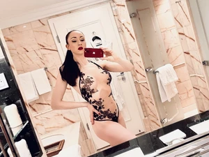 Lady Mephista is taking a selfie in lingerie in a marble bathroom.