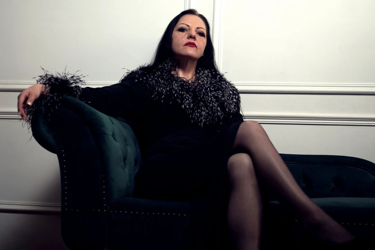 Eine elegant gekleidete Frau auf einer blauen Chaiselongue.