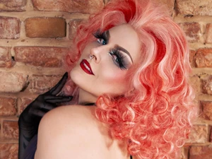 Lady Selina Morgan als Femme Fatale mit elegantem Outfit, pinken Haaren, roten Lippen und selbstbewusstem Ausdruck im BDSM Studio LUX Berlin