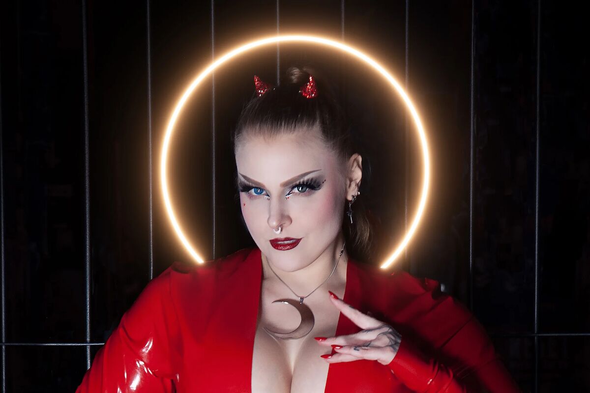Lady Selina Morgan in rotem Latex mit Teufelshörnern und Mond-Schmuck, kraftvolles Dominatrix-Porträt mit Heiligenschein
