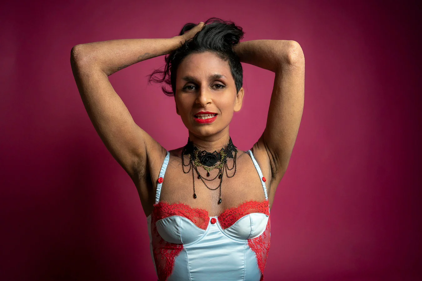 Violet Beau smiling and holding her arms above her head. Her hands are in her hair
